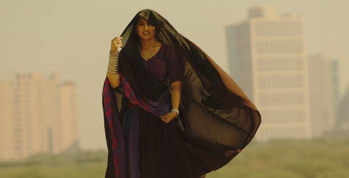 Archie in a flowing black veil against a city skyline